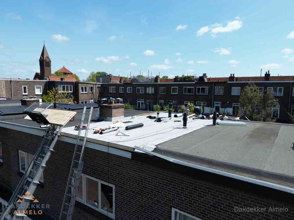 Dakdekkers aan het werk op plat dak in Almelo